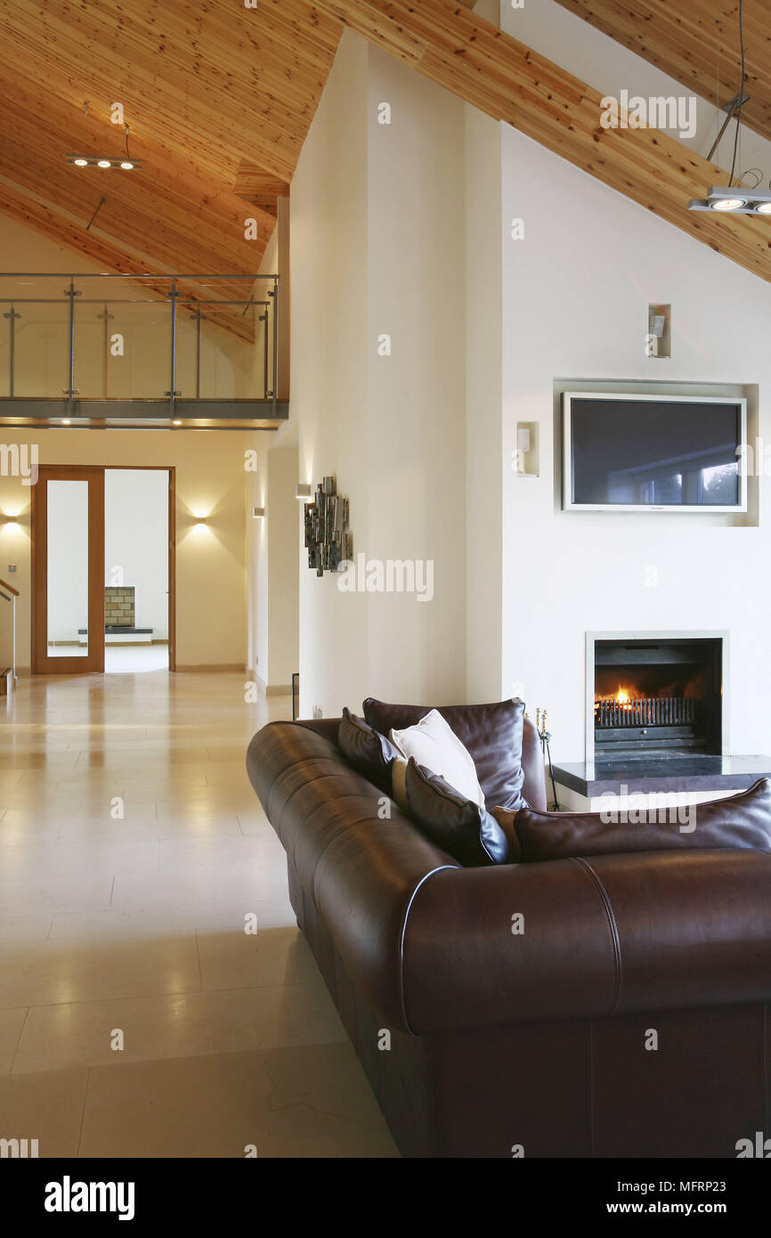 Leather sofa in front of fireplace with lit fire in spacious sitting