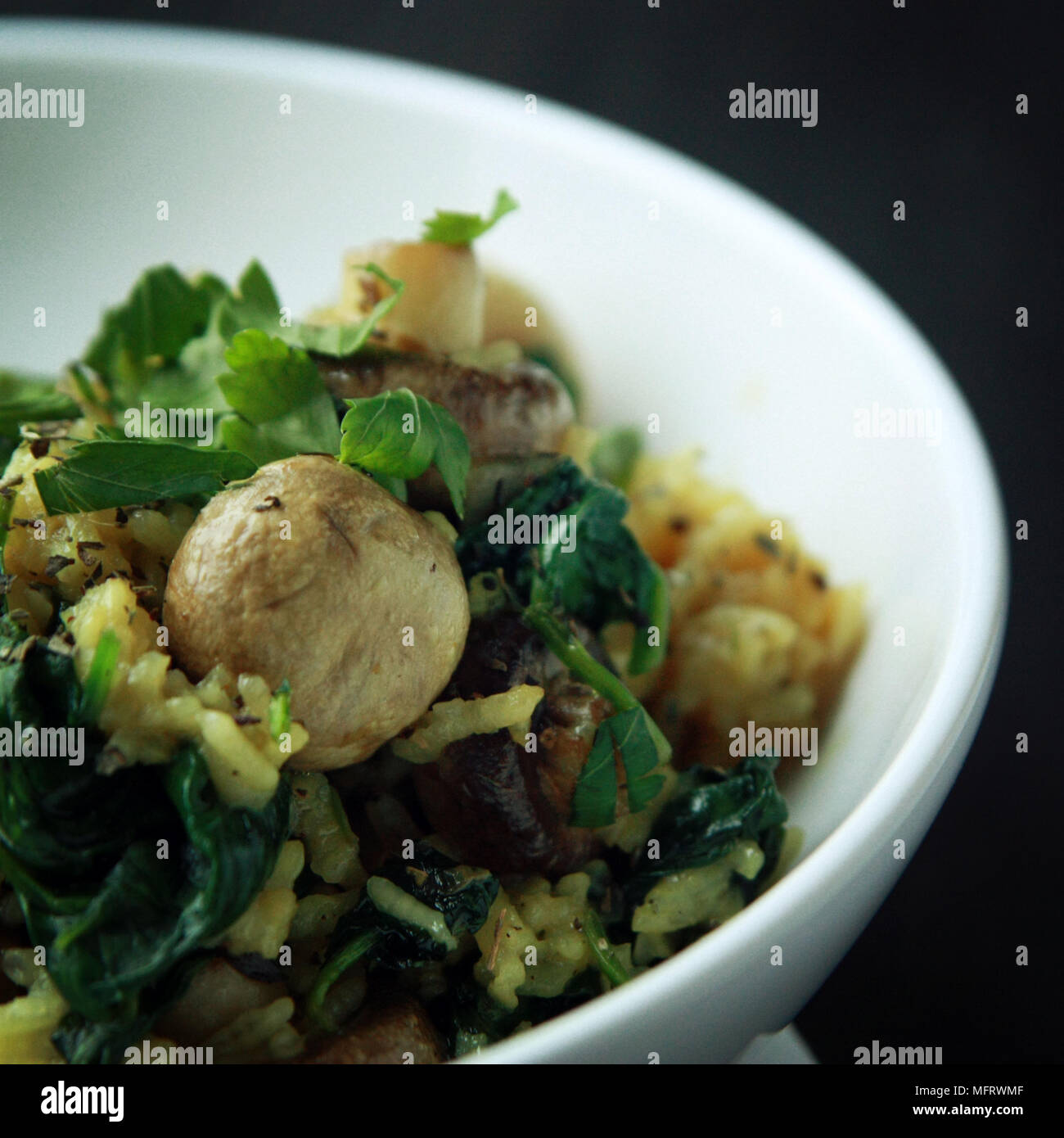 Yellow rice with mushrooms and spinach. Vegan dish. European cuisine. Vegetarian turmeric rice in the white bowl. Meatless. Toned photo. Stock Photo