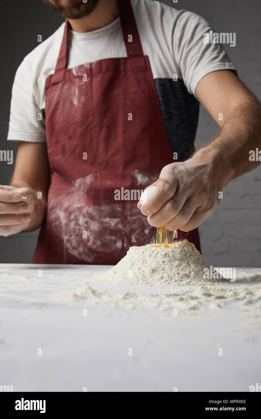 cropped image of chef preparing dough and adding egg to flour Stock Photo