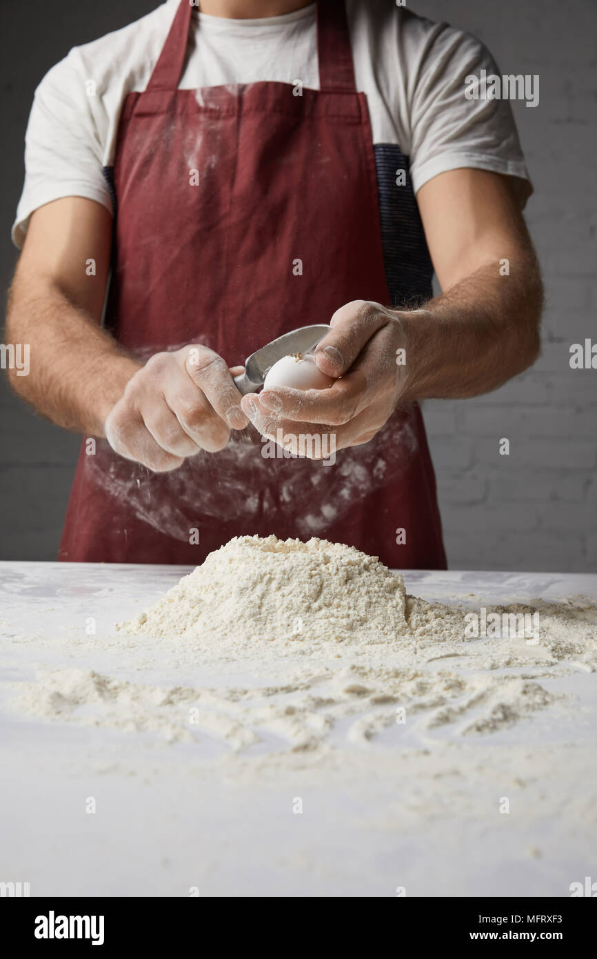 cropped image of chef preparing dough and breaking egg Stock Photo