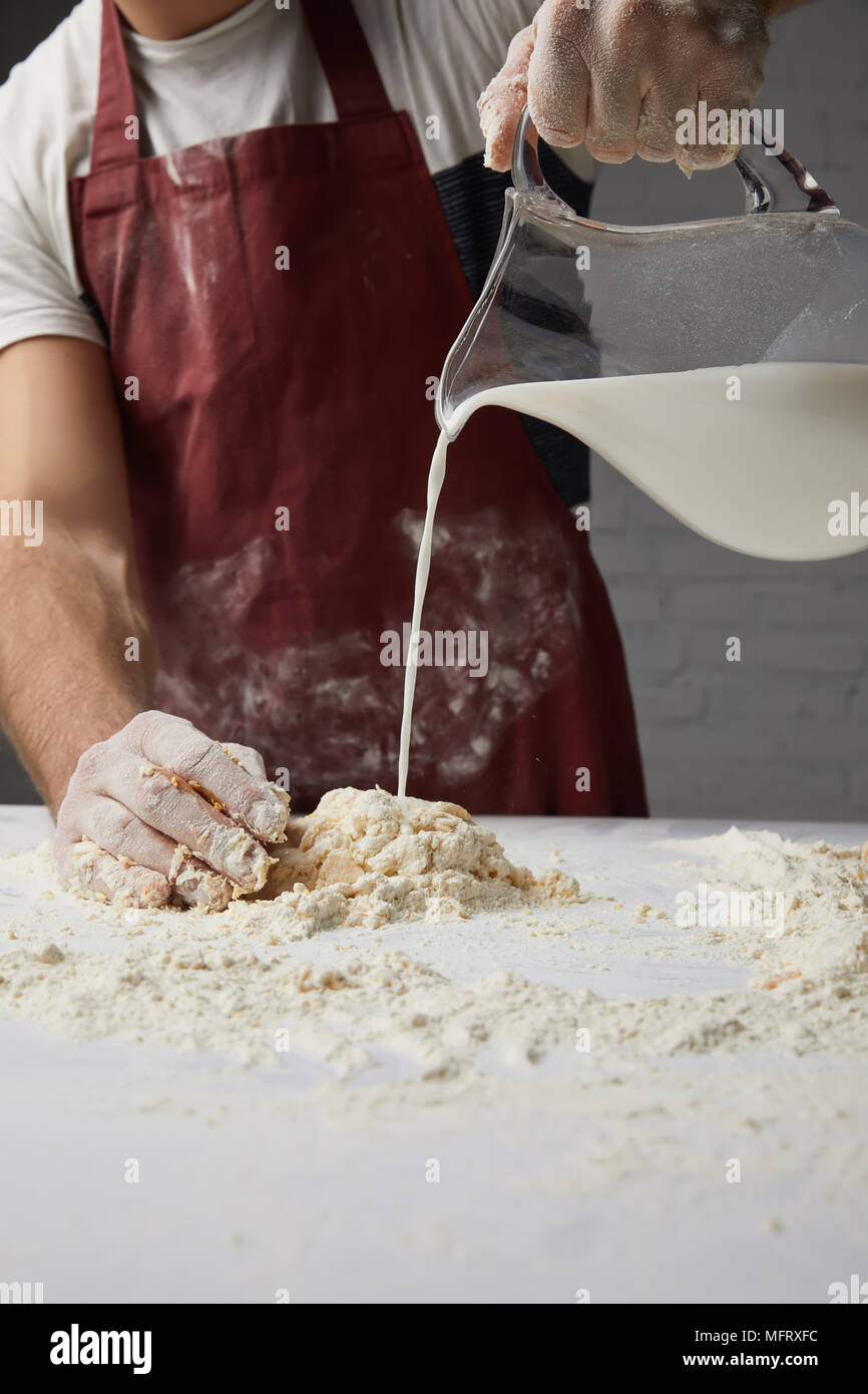 cropped image of chef preparing dough and pouring milk Stock Photo