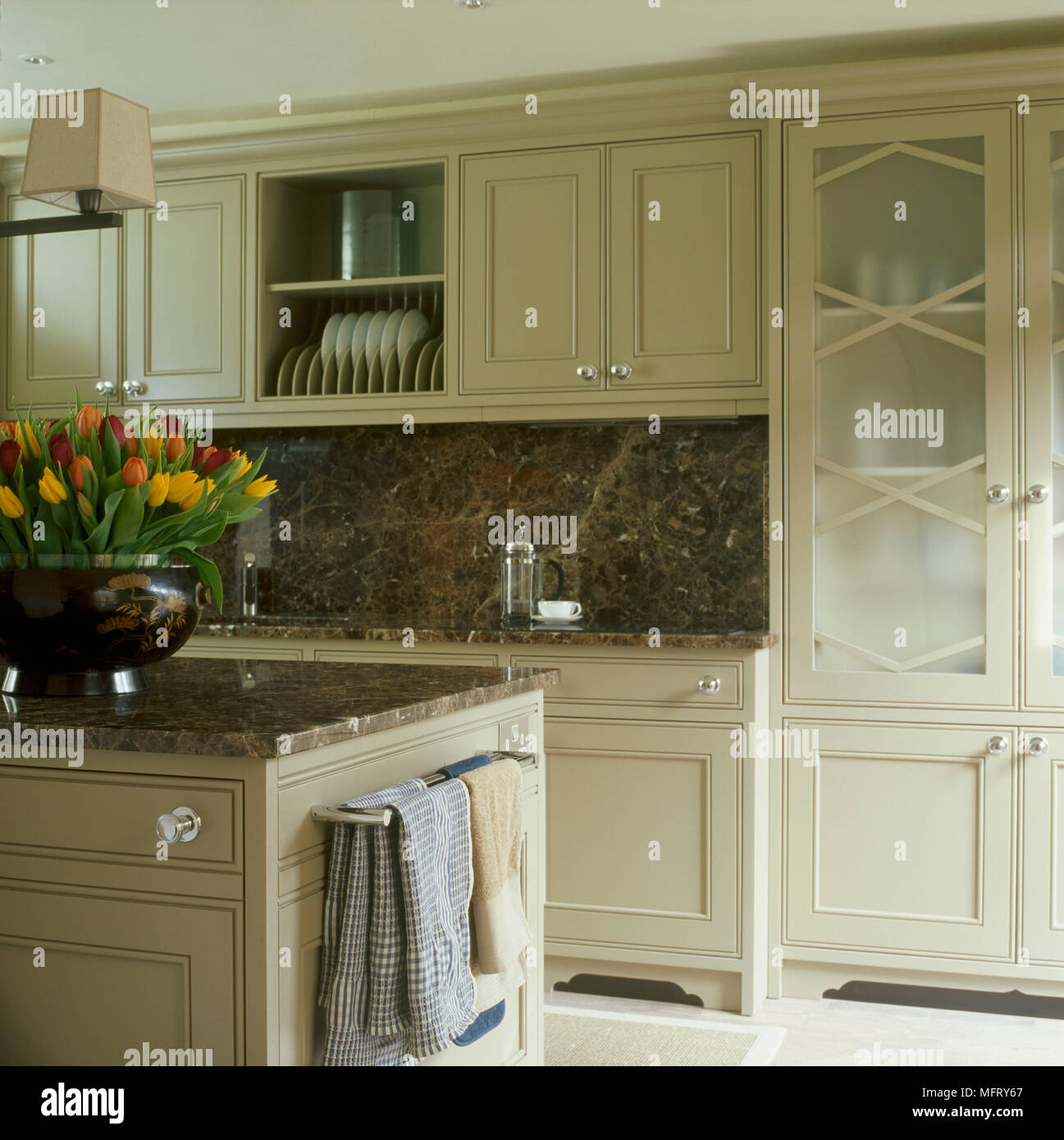 A detail of a modern kitchen painted units granite work tops and splash back glass fronted cabinets Stock Photo