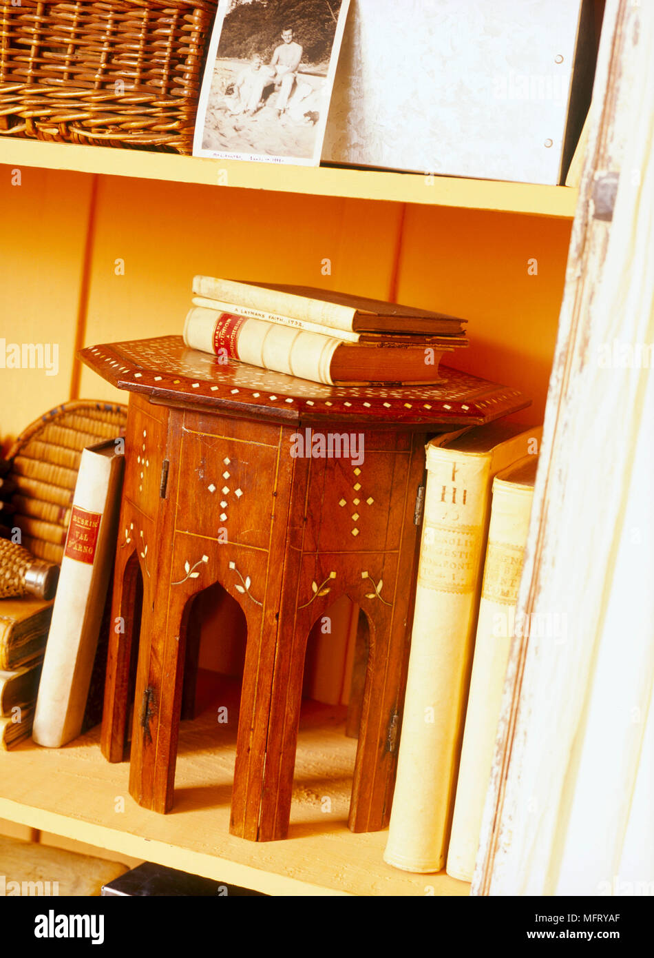 A detail of items on a shelf a small wooden octagonal table books Stock ...