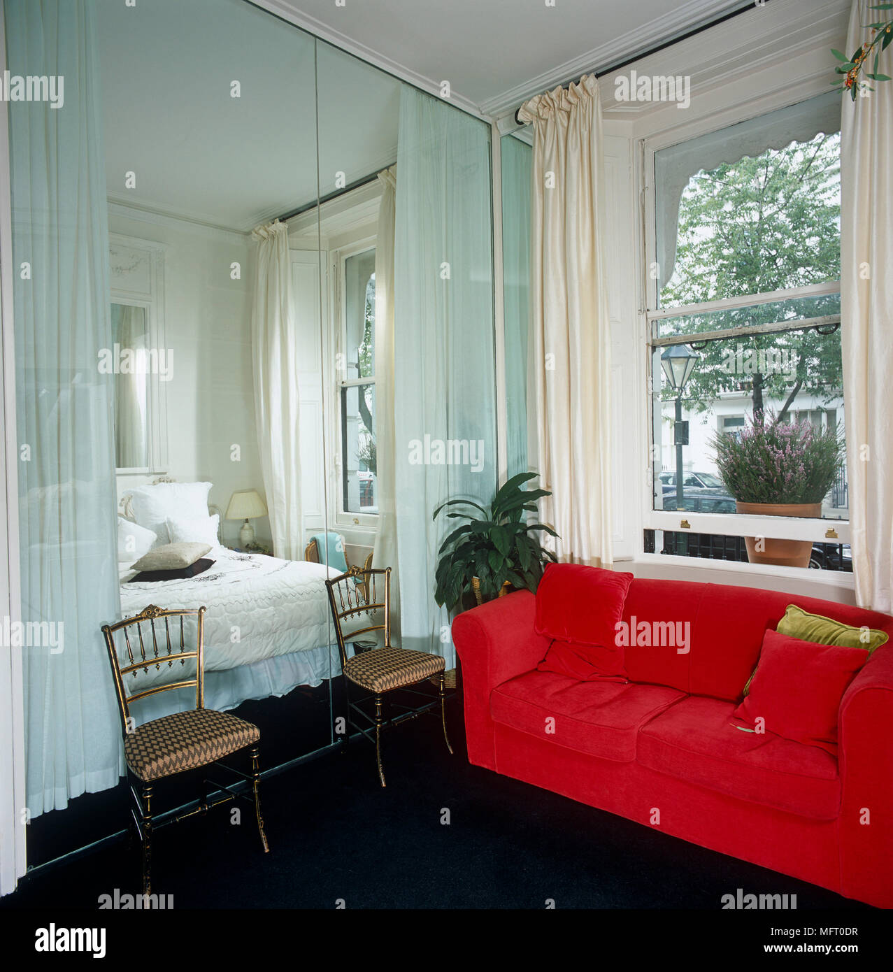 Red sofa and pair of chairs in front of mirrored wardrobes