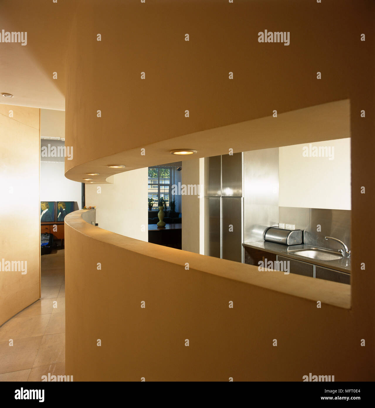 Modern kitchen viewed through curved wall opening from hallway Stock Photo Alamy