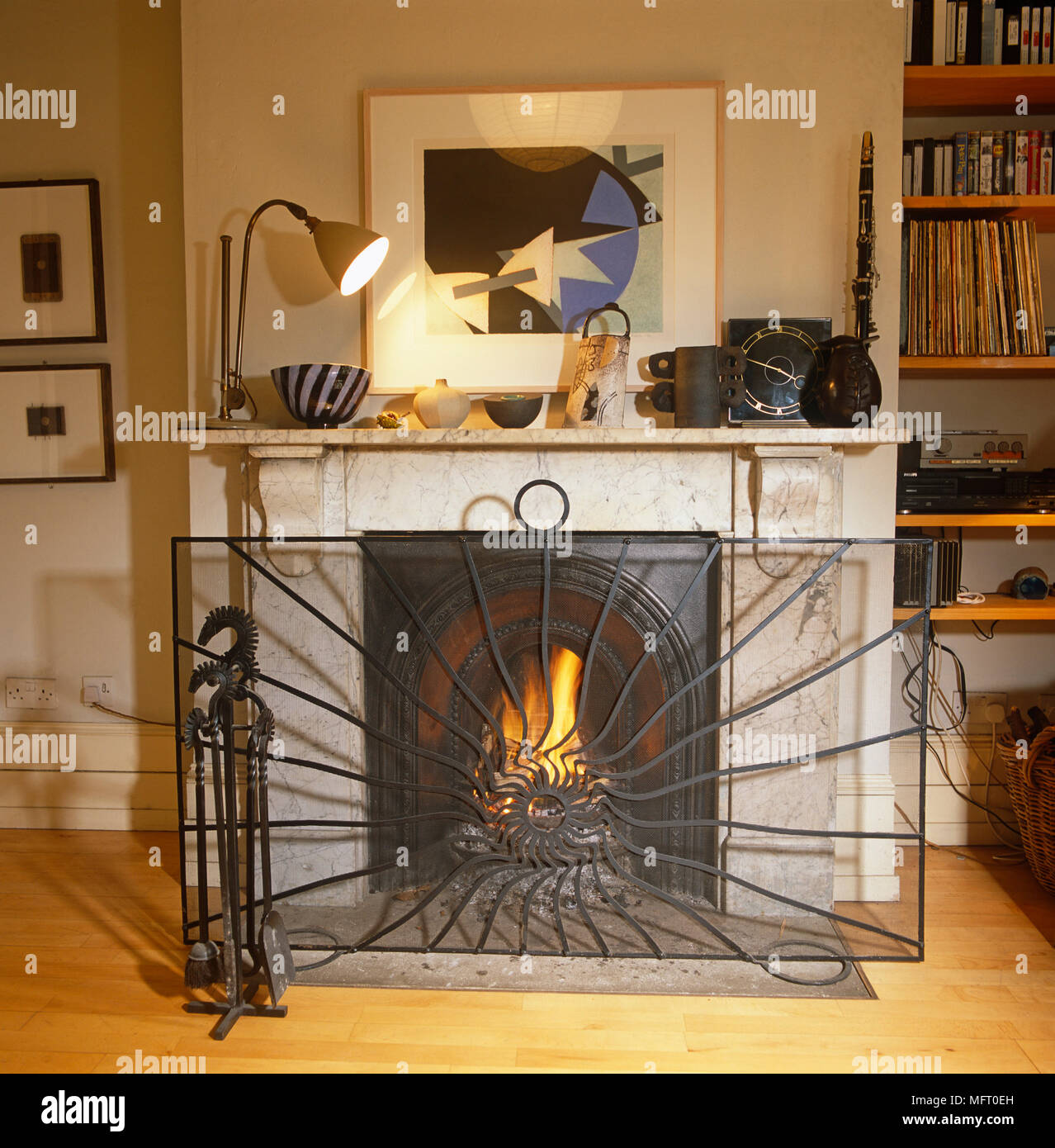 Wrought Iron Fireguard In Front Of Stone Fireplace With Lit Fire