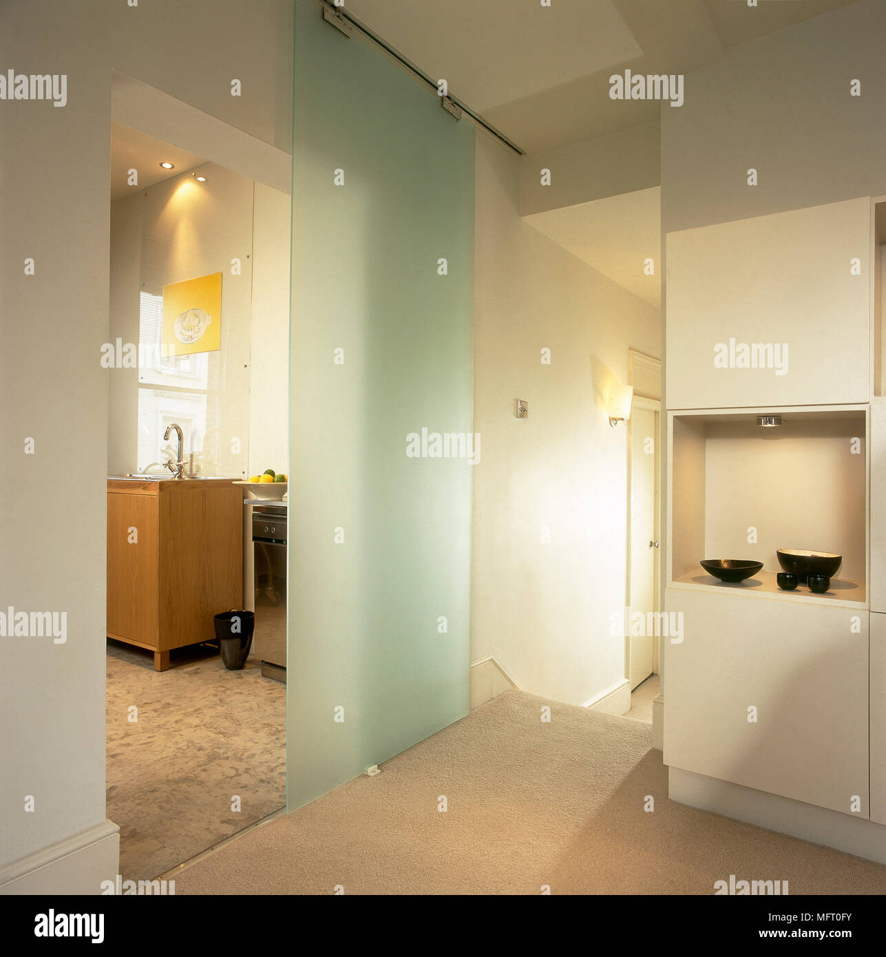 Modern, carpeted hallway with sliding, opaque glass door. Stock Photo