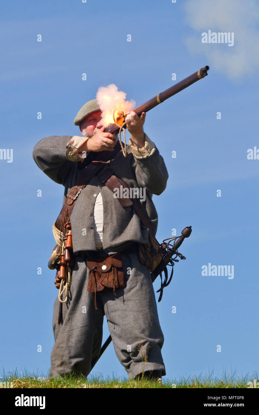 A re-enactor firing a musket in the uniform of a 17th century covenanter of Colonel Hugh Fraser's dragoons. Stock Photo