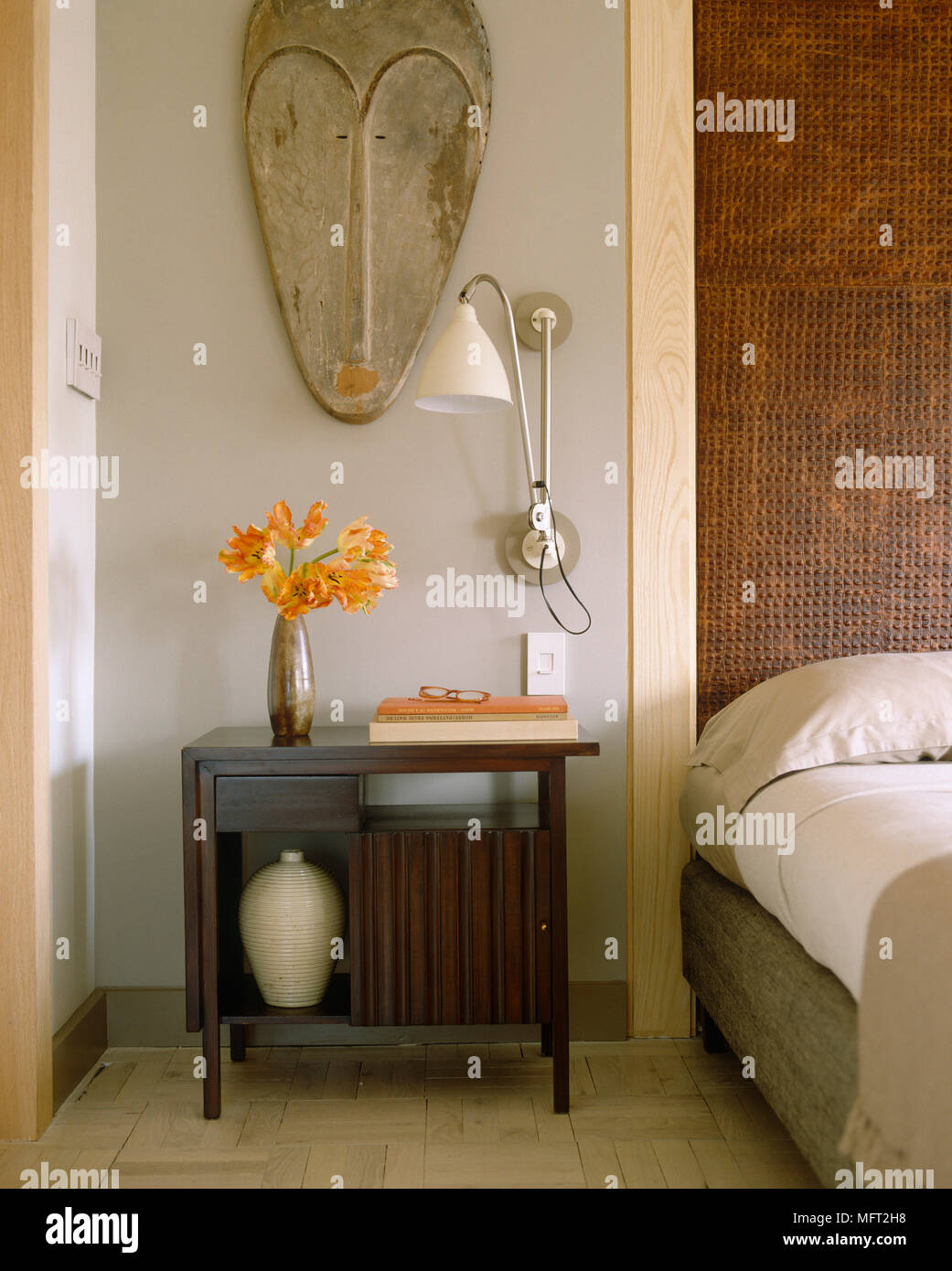 Wall lamp above bedside next to double bed with textured wall