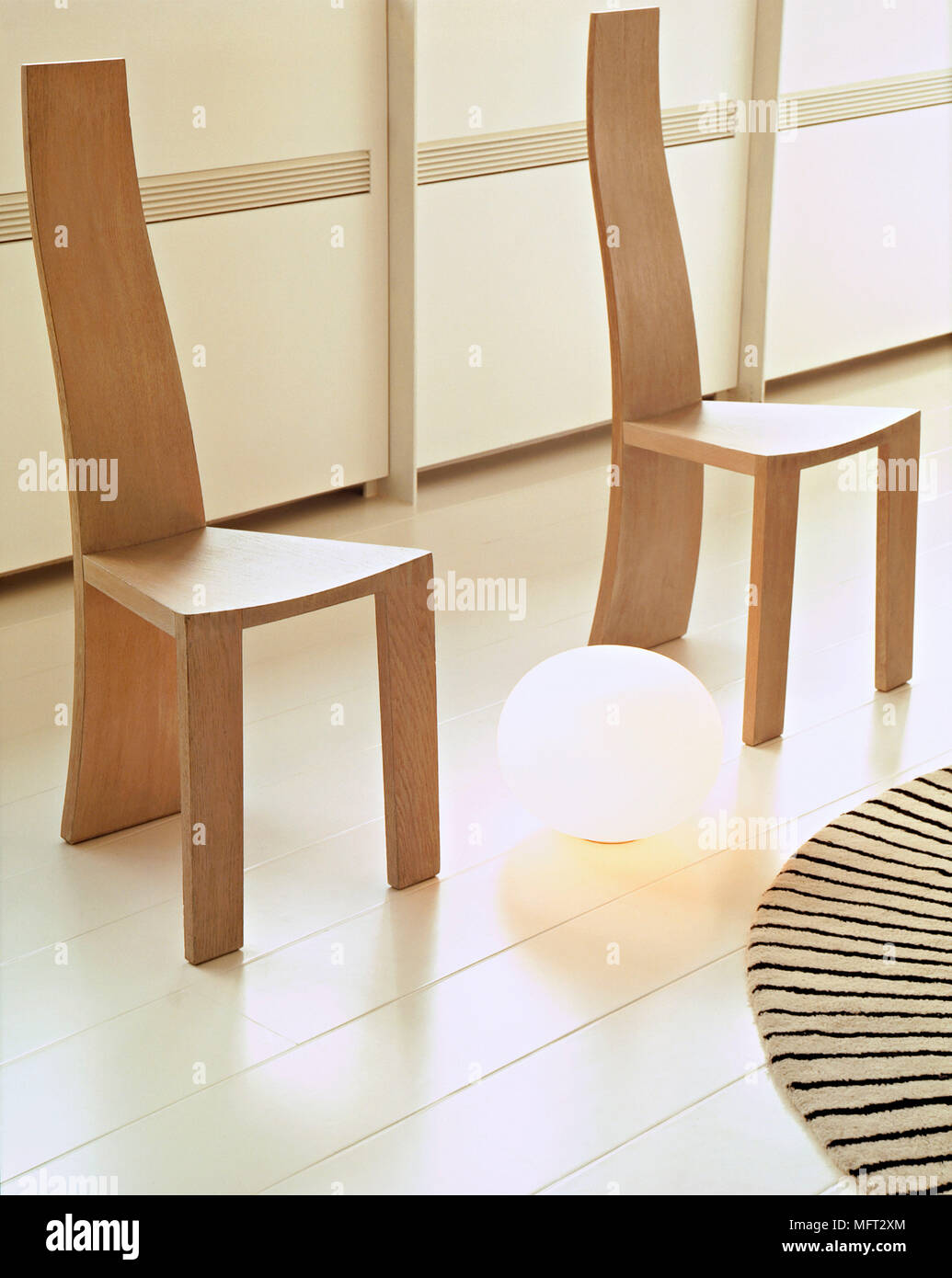 Two Modern Wooden Chairs Either Side Of A Spherical Floor Light