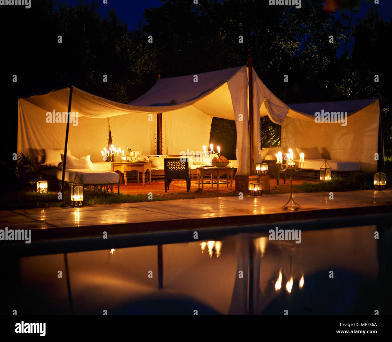 Moroccan hotel outdoor entertaining lit marquee at night by pool lanterns     outdoors pools Stock Photo