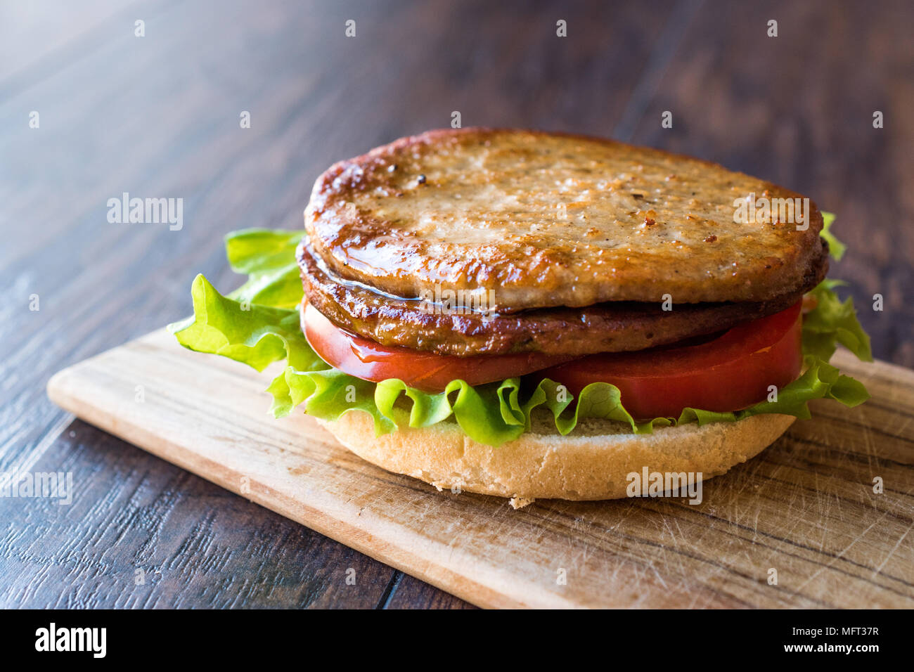 Open Double Burger with Turkey Meat, Lettuce and Tomatoes on Wooden Surface. FastFood Concept. Stock Photo