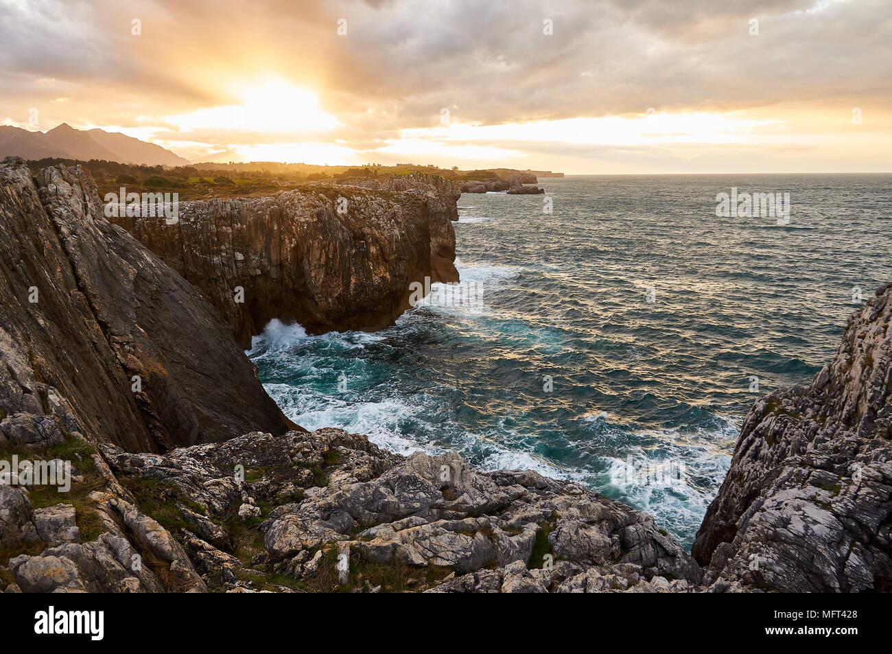 Scenery view of the Cantabrian sea coastline and cliffs in a cloudy sunset near Gulpiyuri beach (Naves, Llanes, Oriente, Asturias, Spain) Stock Photo