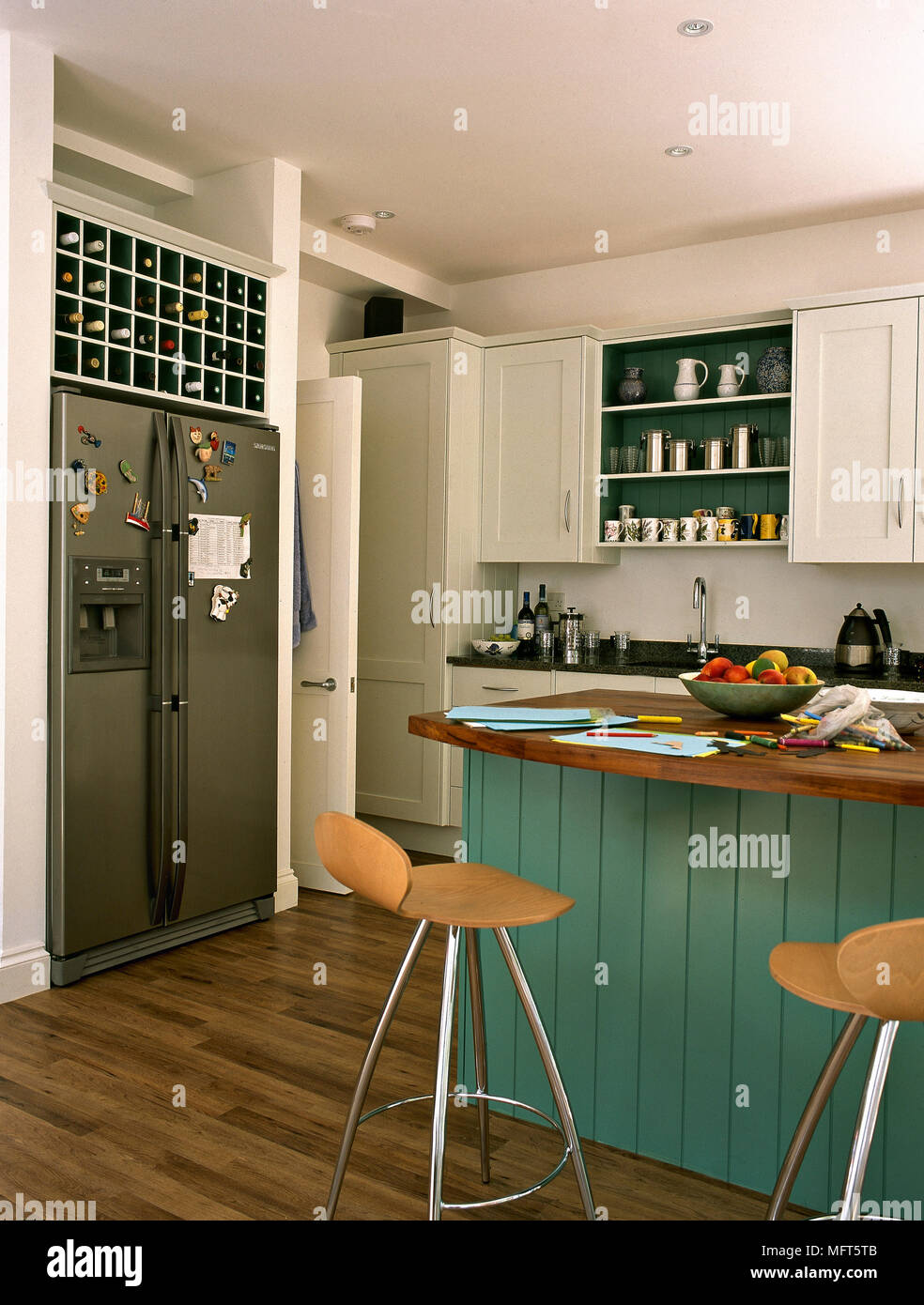 Double fridge with fridge magnets below wine rack in kitchen with panelled  breakfast bar and stools Stock Photo - Alamy