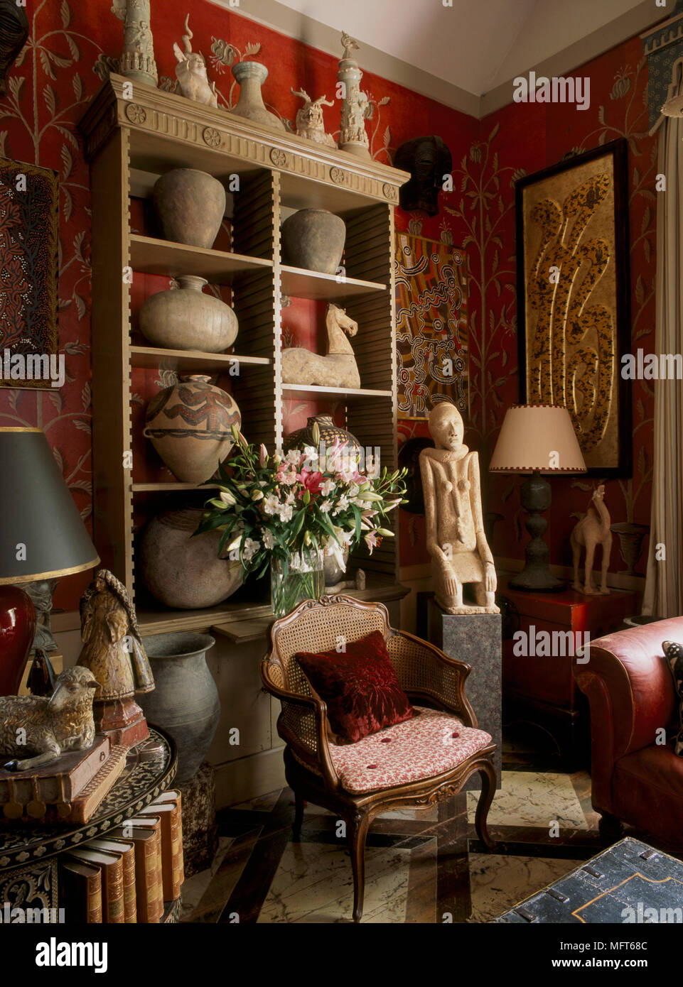 A detail of a traditional, red sitting room, a display of pottery vases,  figurines, statues and antiquities Stock Photo - Alamy