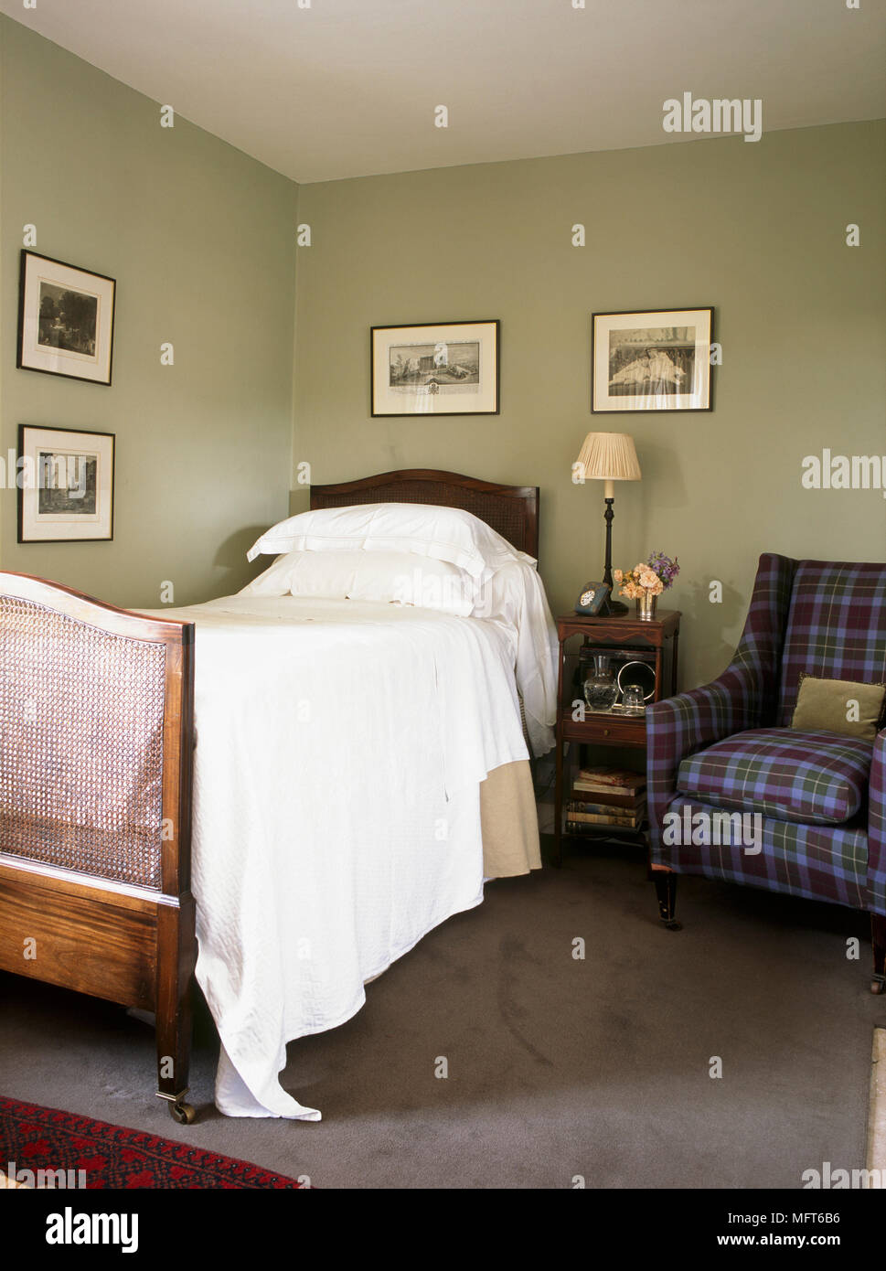 A traditional, green bedroom with wooden single bed, armchair with
