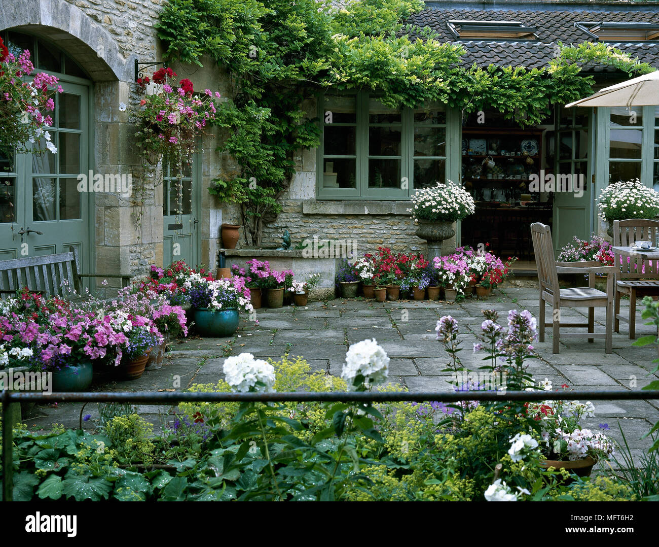 Exterior of the back terrace of a stone country house with tile floor, potted flowers, and climbing vines. Stock Photo