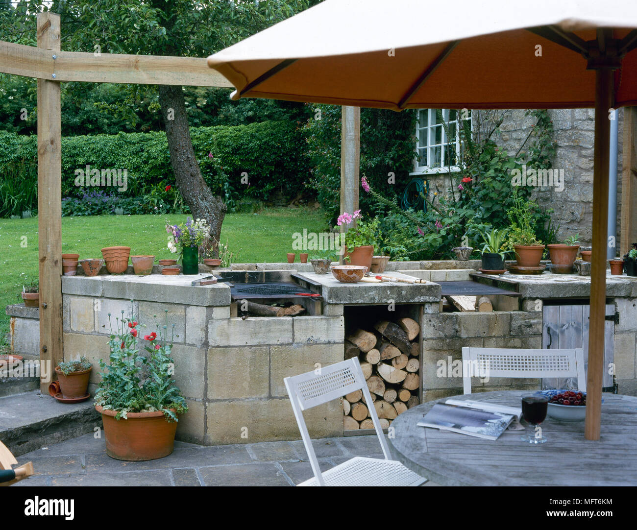 Backyard with a brick outdoor barbecue, flagstone patio, and a table and chairs under an umbrella. Stock Photo