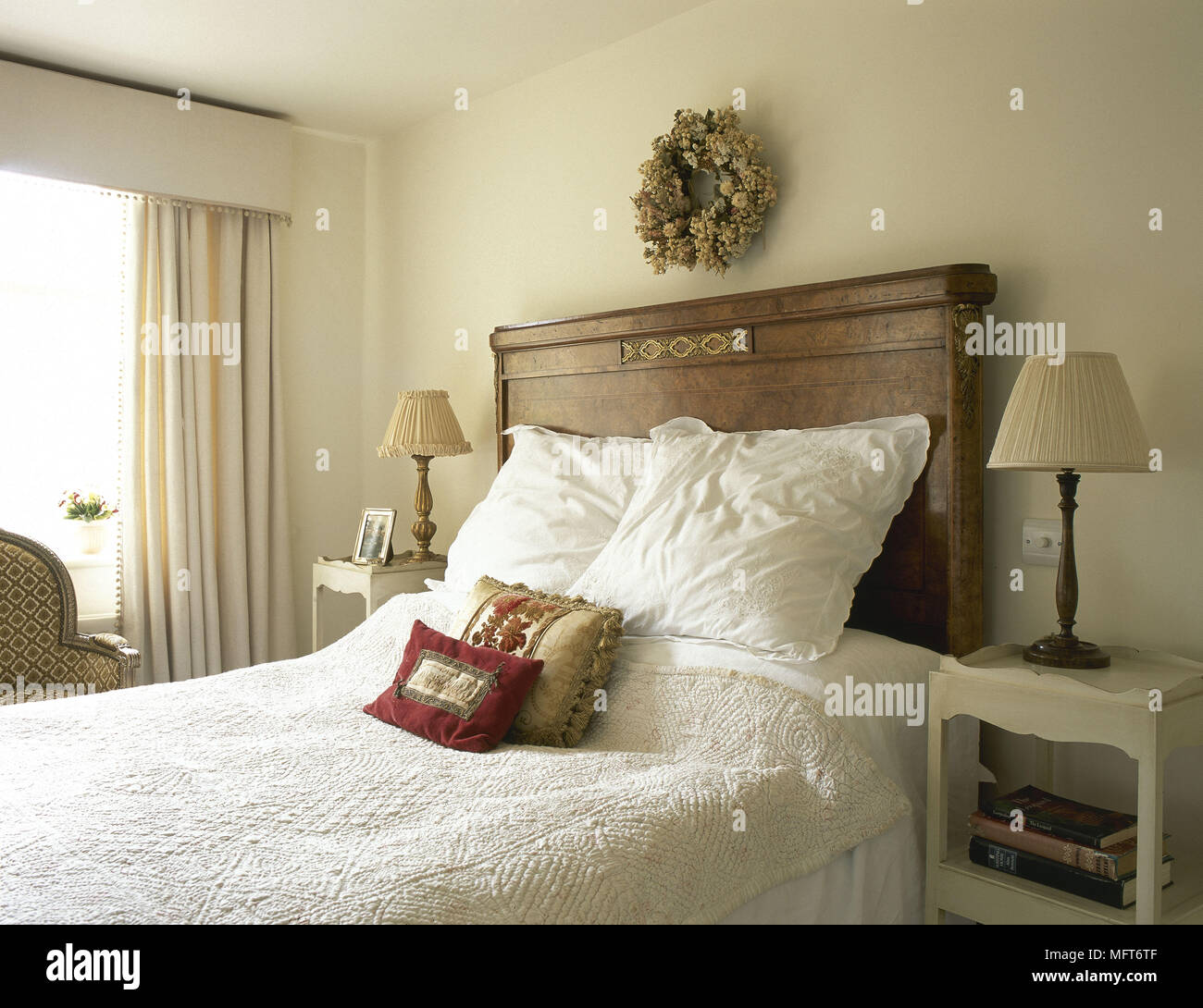 Neutral coloured bedroom with antique wooden headboard and white linen