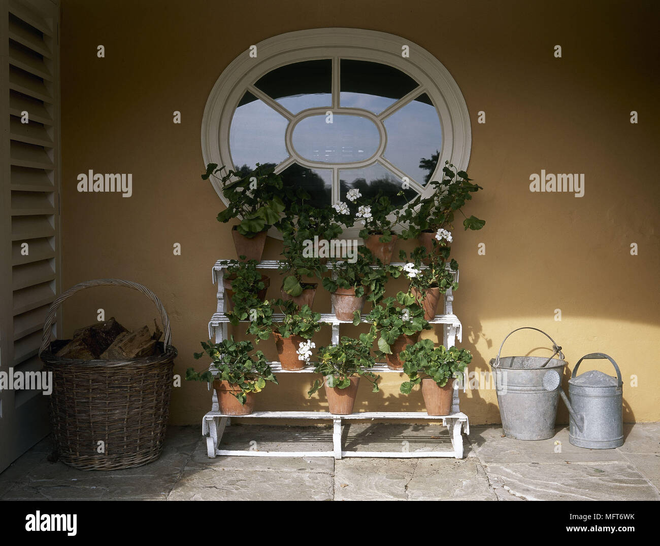 Paved patio area pot plant stand watering can  patios flowers pots Stock Photo