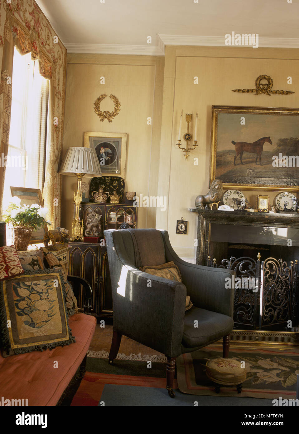 A traditional yellow sitting room with fireplace curtain pelmets sofa upholstered armchair Stock Photo