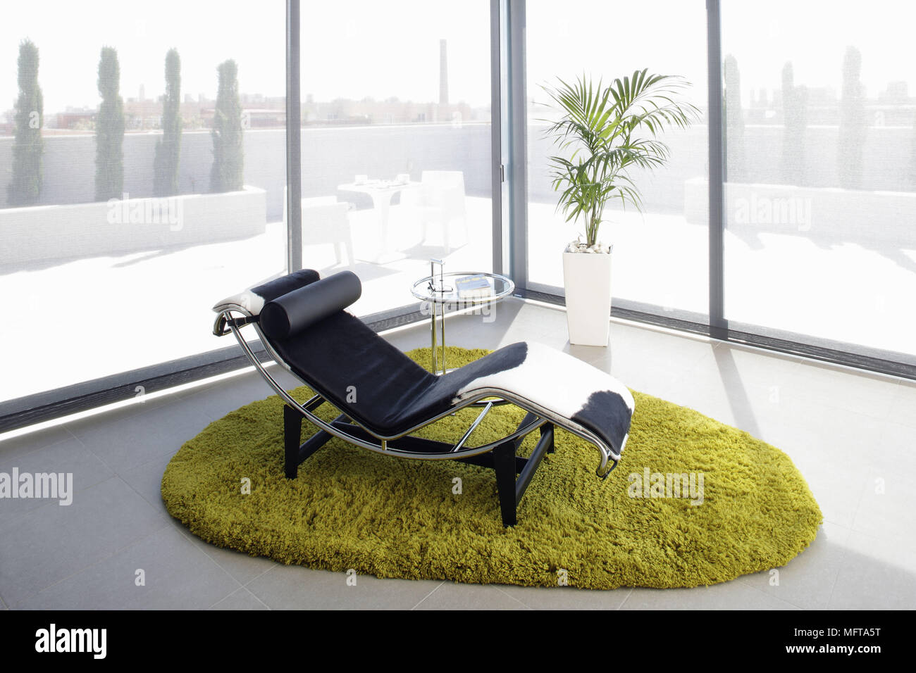 Le Corbusier leather recliner set on lime green rug in corner of ...