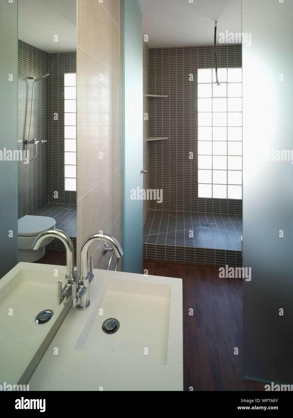 Mirror above washbasin in contemporary bathroom with shower area Stock