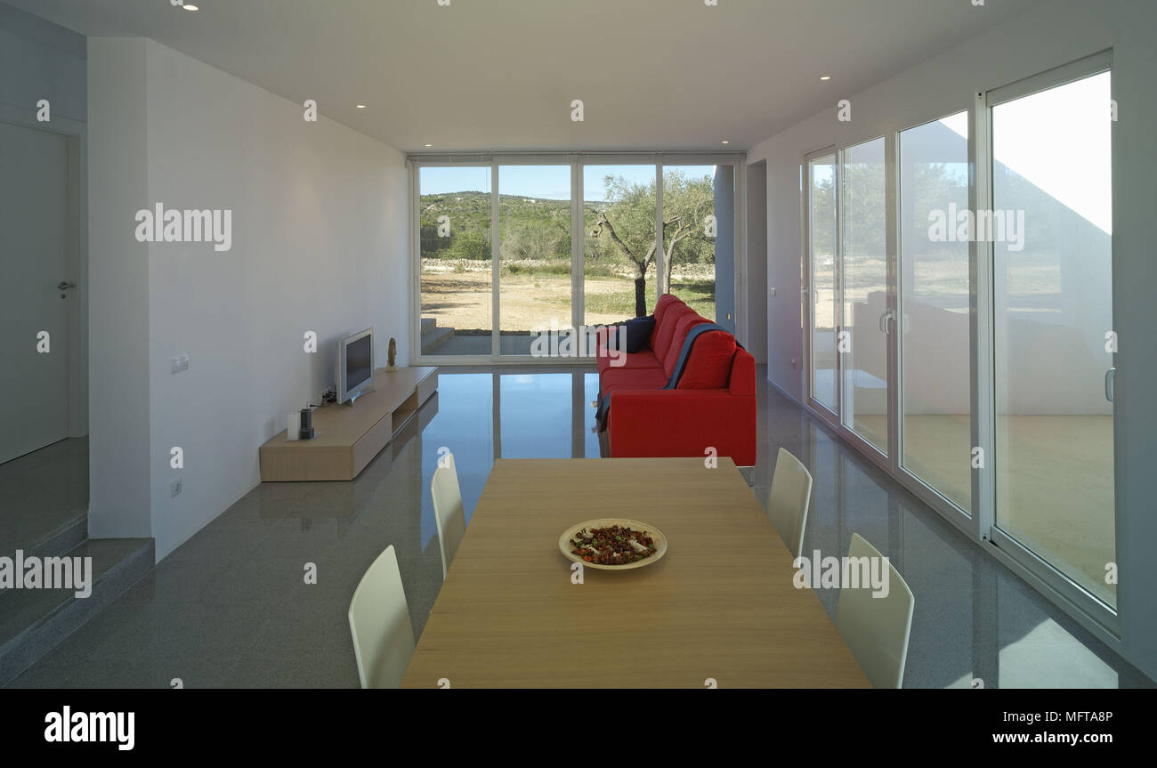 Red sofa facing television on unit in modern open plan sitting room with dining area Stock Photo