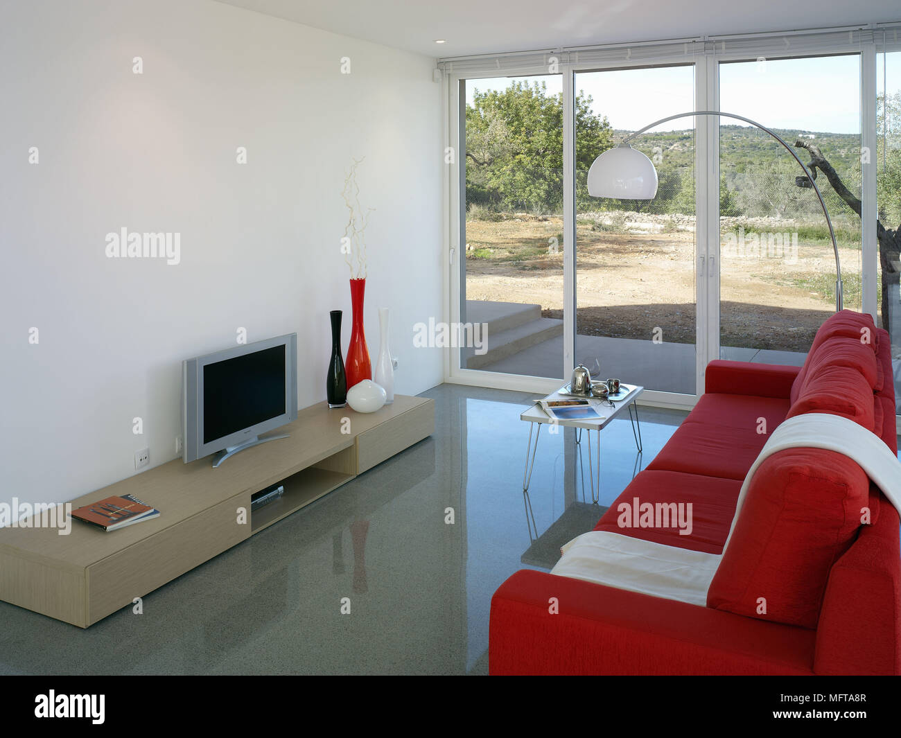 Red sofa facing television on unit in modern sitting room Stock Photo Alamy