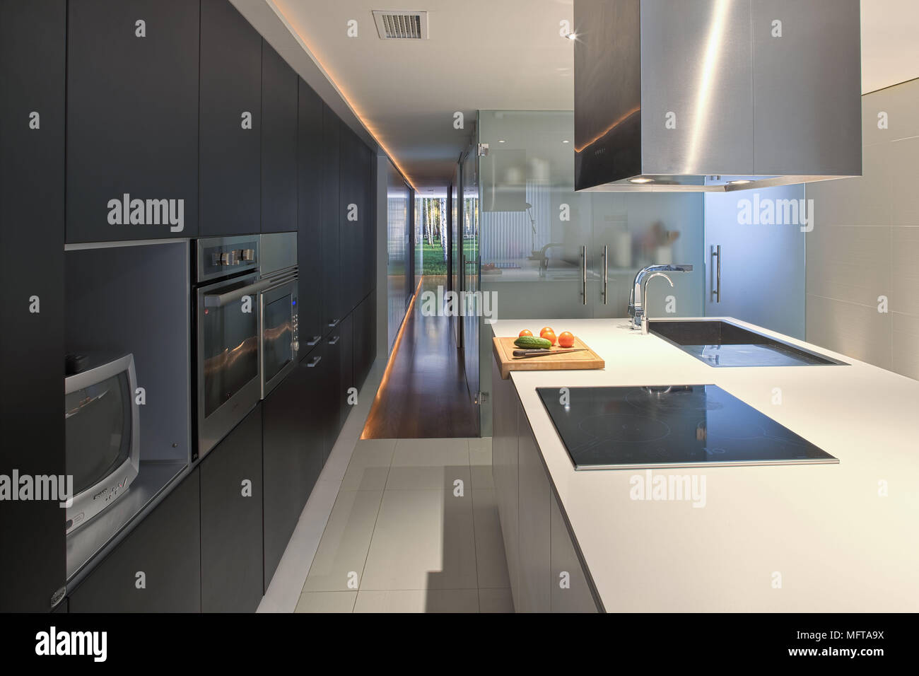 Stainless steel extractor fan above ceramic hob in central island unit in spacious contemporary