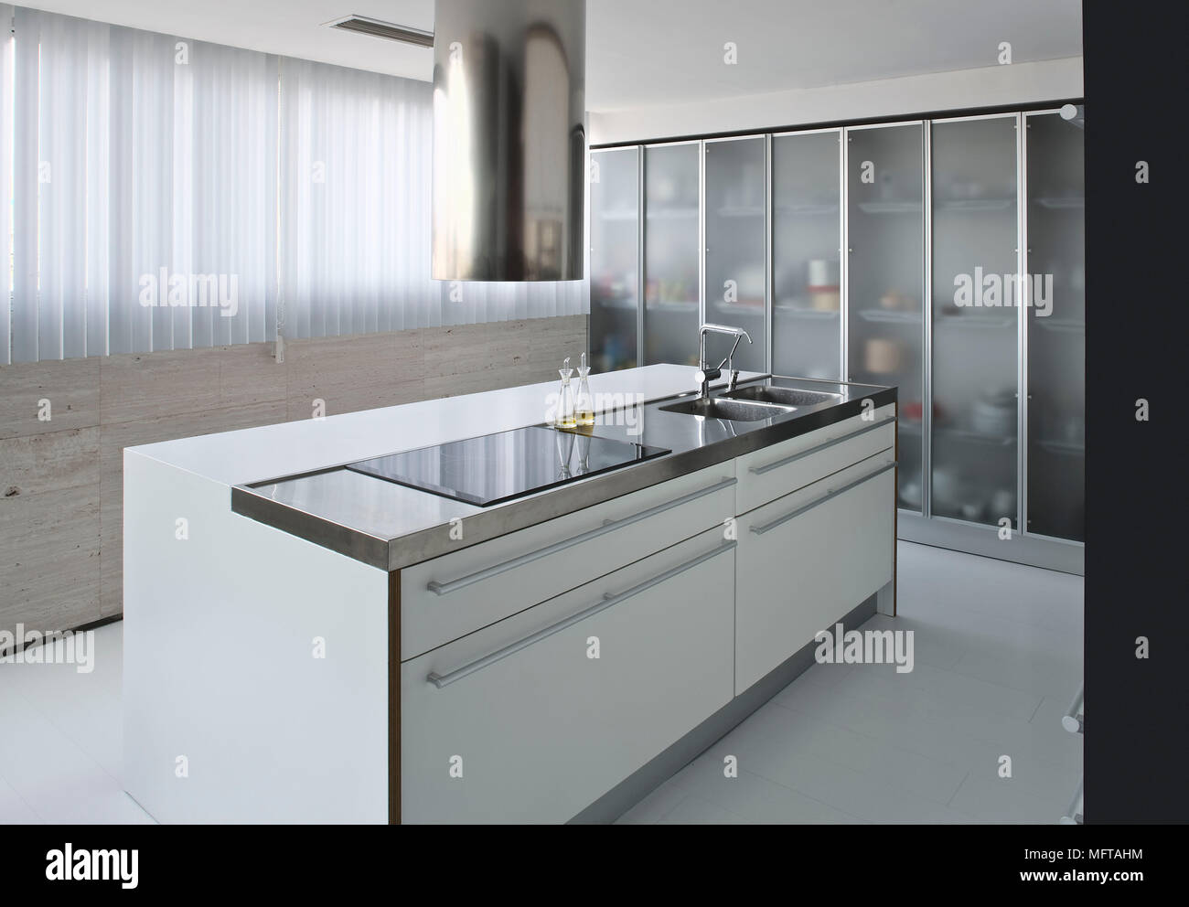 Extractor fan above hob set in central island unit in modern kitchen