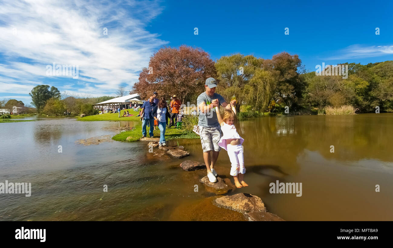 Johannesburg, South Africa, 05/10/2014,  Father and daughter crossing a stream at The Winter Sculpture Fair at Nirox Sculpture Park Stock Photo