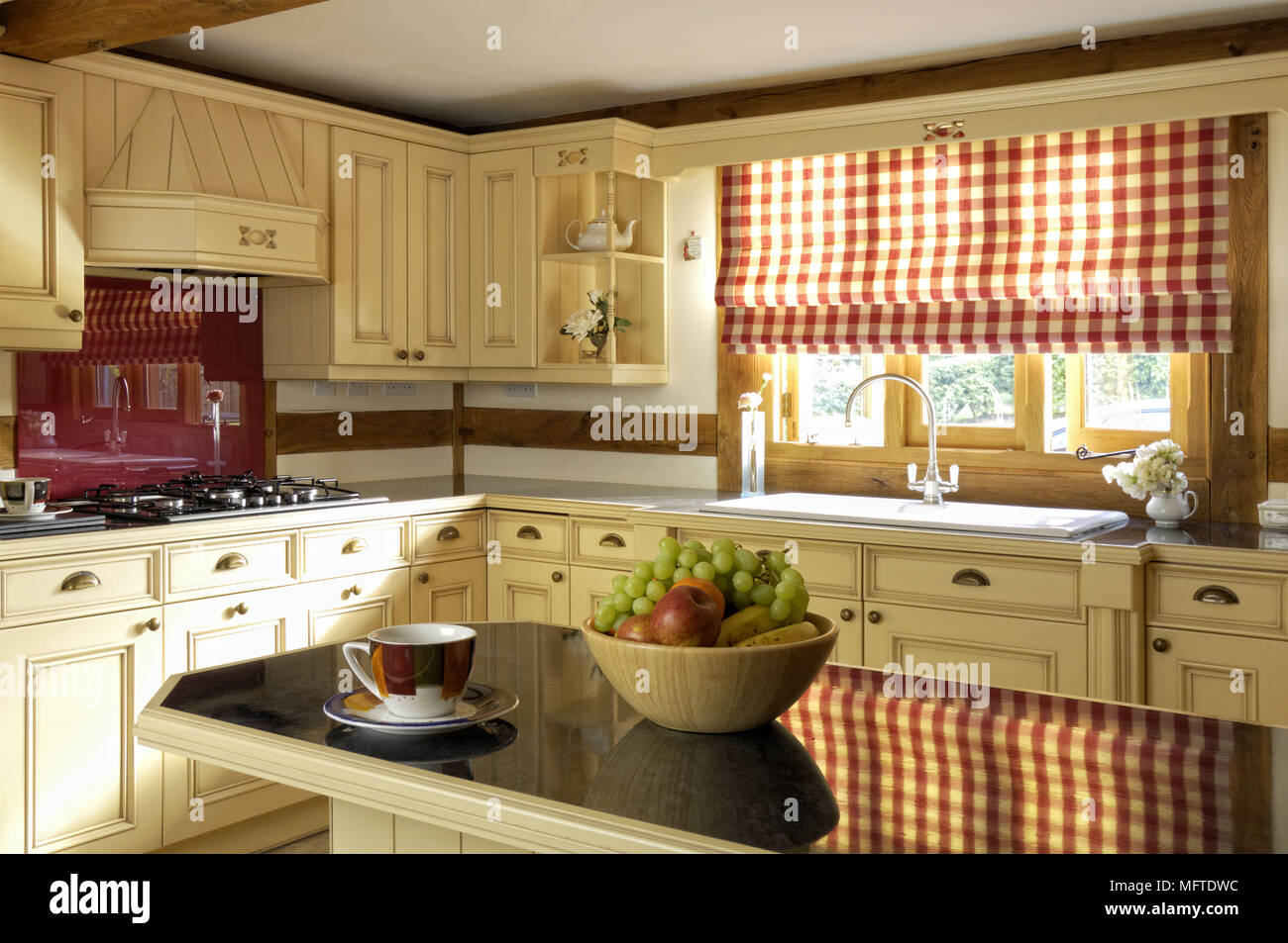 Modern country style kitchen with red check patterned roman blind at window Stock Photo