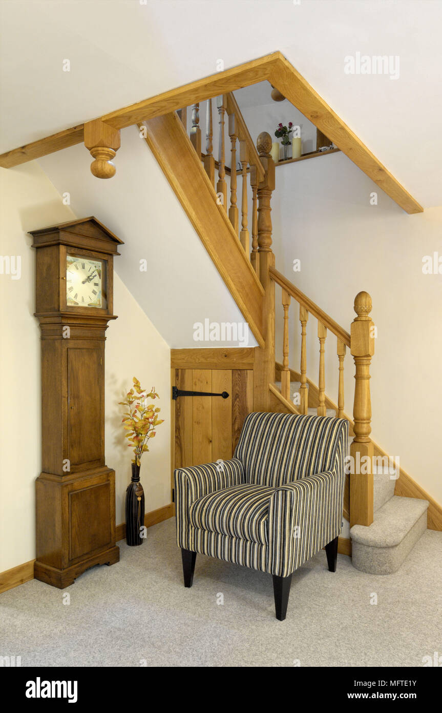 Upholstered armchair next to grandfather clock in hallway Stock Photo