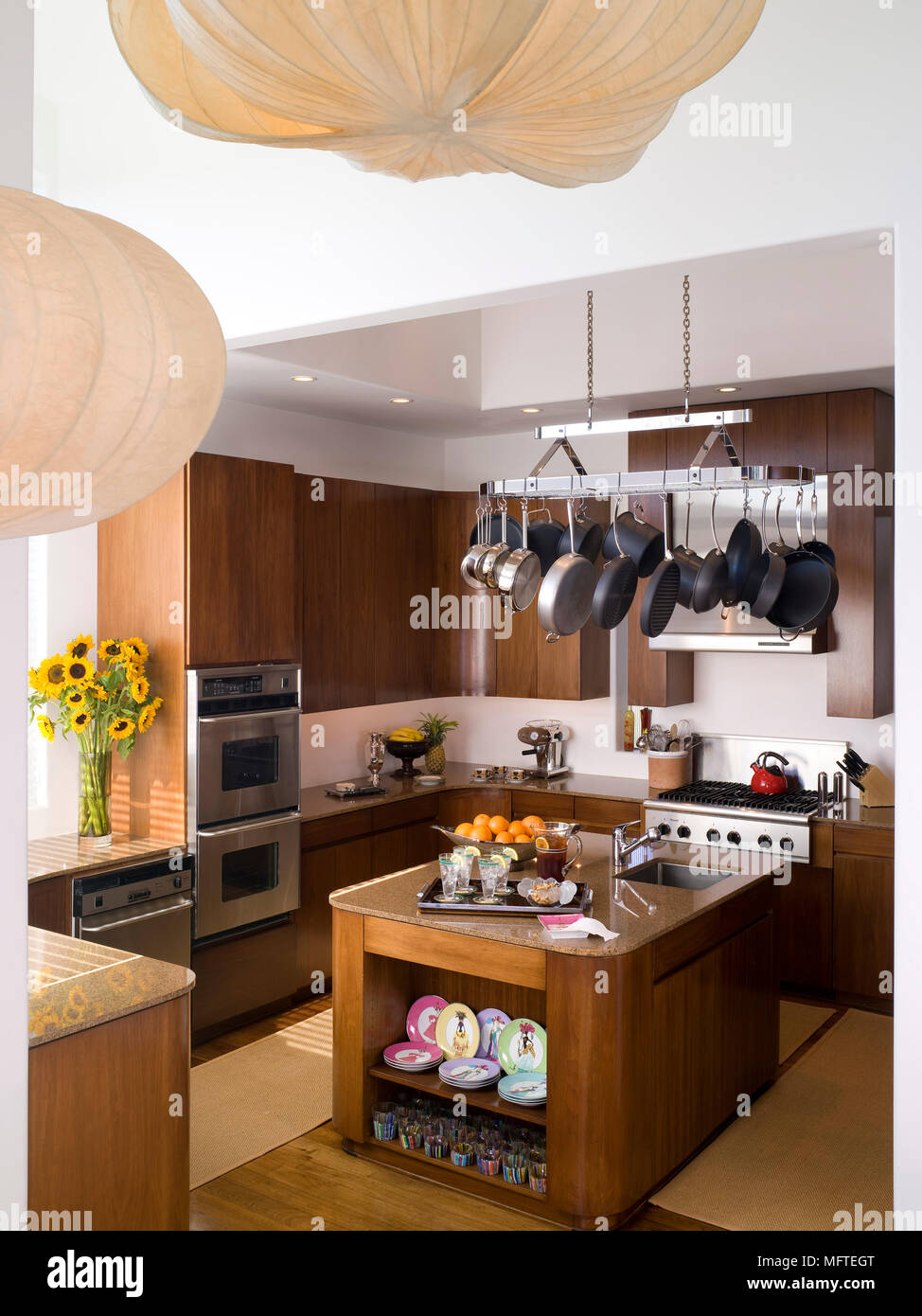Pots and pans hanging above centre island unit in modern kitchen Stock