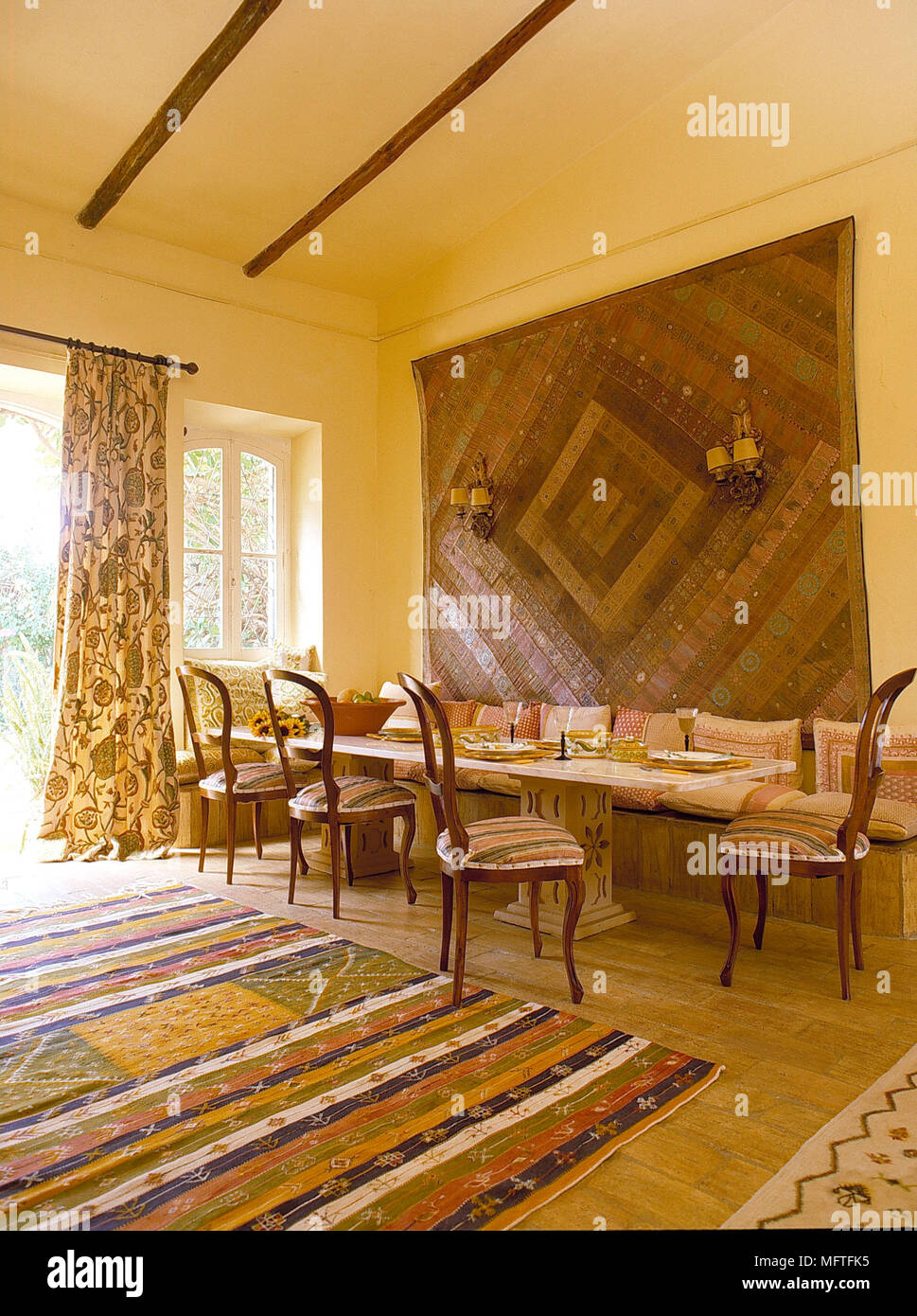 Patterned rug and geometric wall hanging in dining room with high beamed ceiling Stock Photo