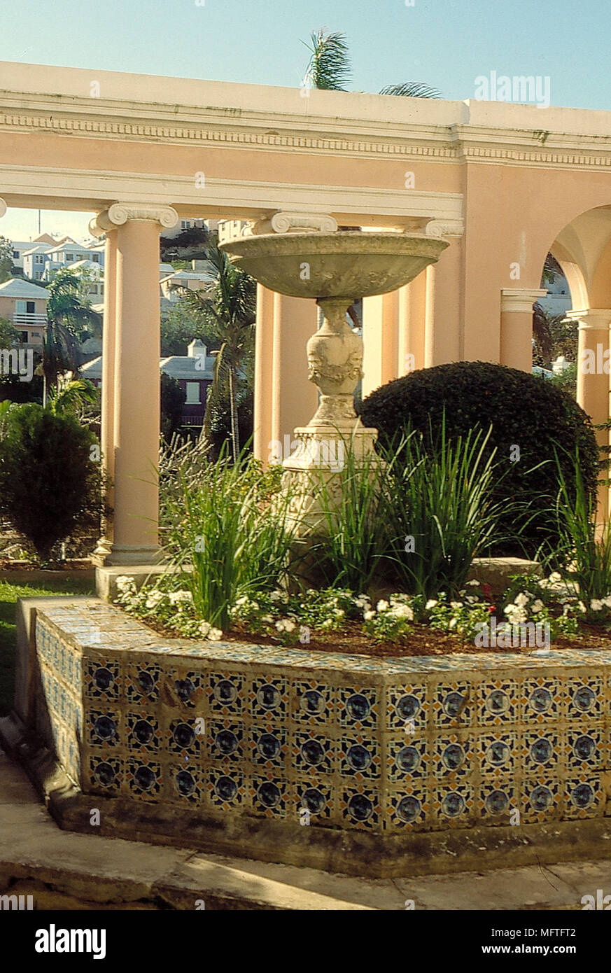 Tiled octagonal raised flower bed with plants and birdbath Stock Photo