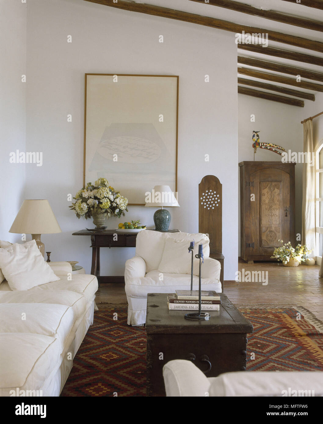 Traditional sitting room with white walls sloping beamed ceiling sofa
