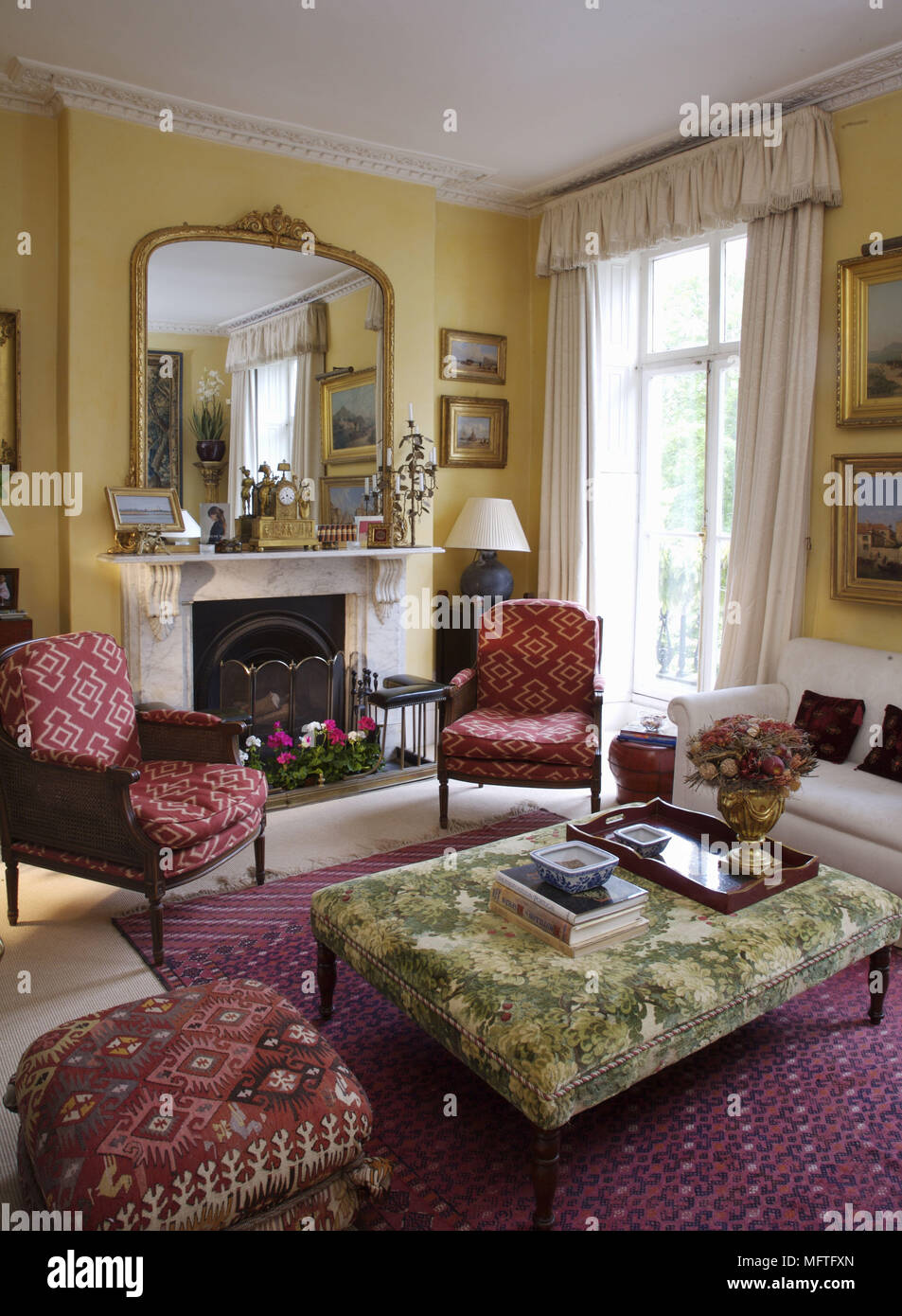 Upholstered chairs arranged in front of fireplace in traditional style sitting room Stock Photo