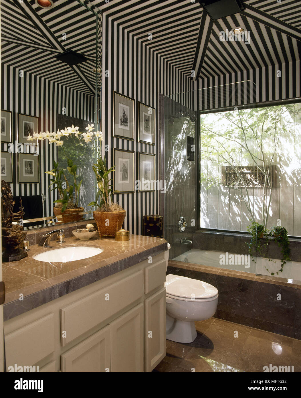 Bathroom with striped wallpaper and washbasin set in marble top unit USA Stock Photo