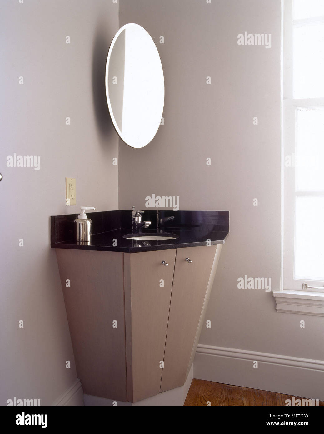 Detail of bathroom with corner wash basin under oval mirror USA ...