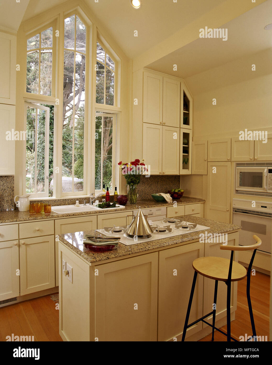 https://c8.alamy.com/comp/MFTGCA/modern-white-kitchen-with-breakfast-bar-and-gothic-style-window-MFTGCA.jpg