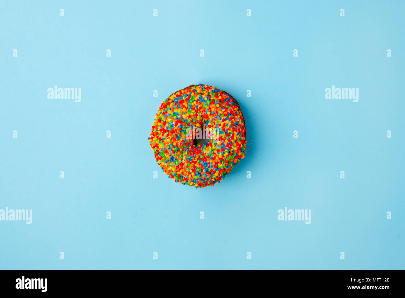 Donut glazed with sprinkles on a blue background. Modern flat lay photo ...
