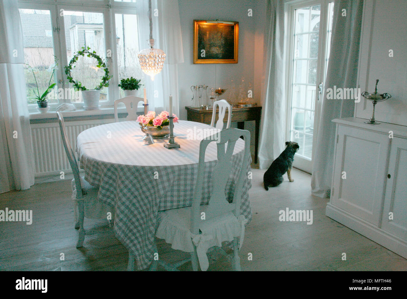 Table with check cloth and white wood chairs in Swedish style dining room Stock Photo