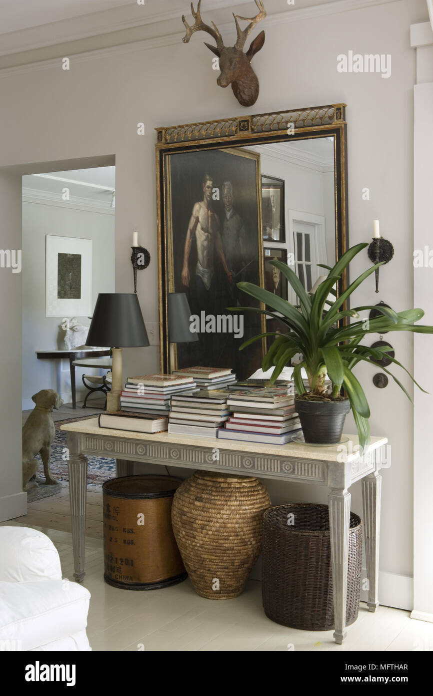 Mirror above table displaying books and houseplant Stock Photo Alamy