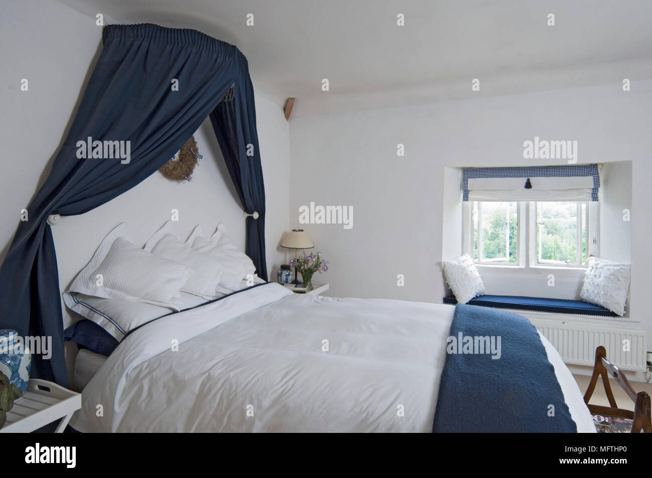 Double bed with fabric canopy and coordinating furnishings Stock Photo