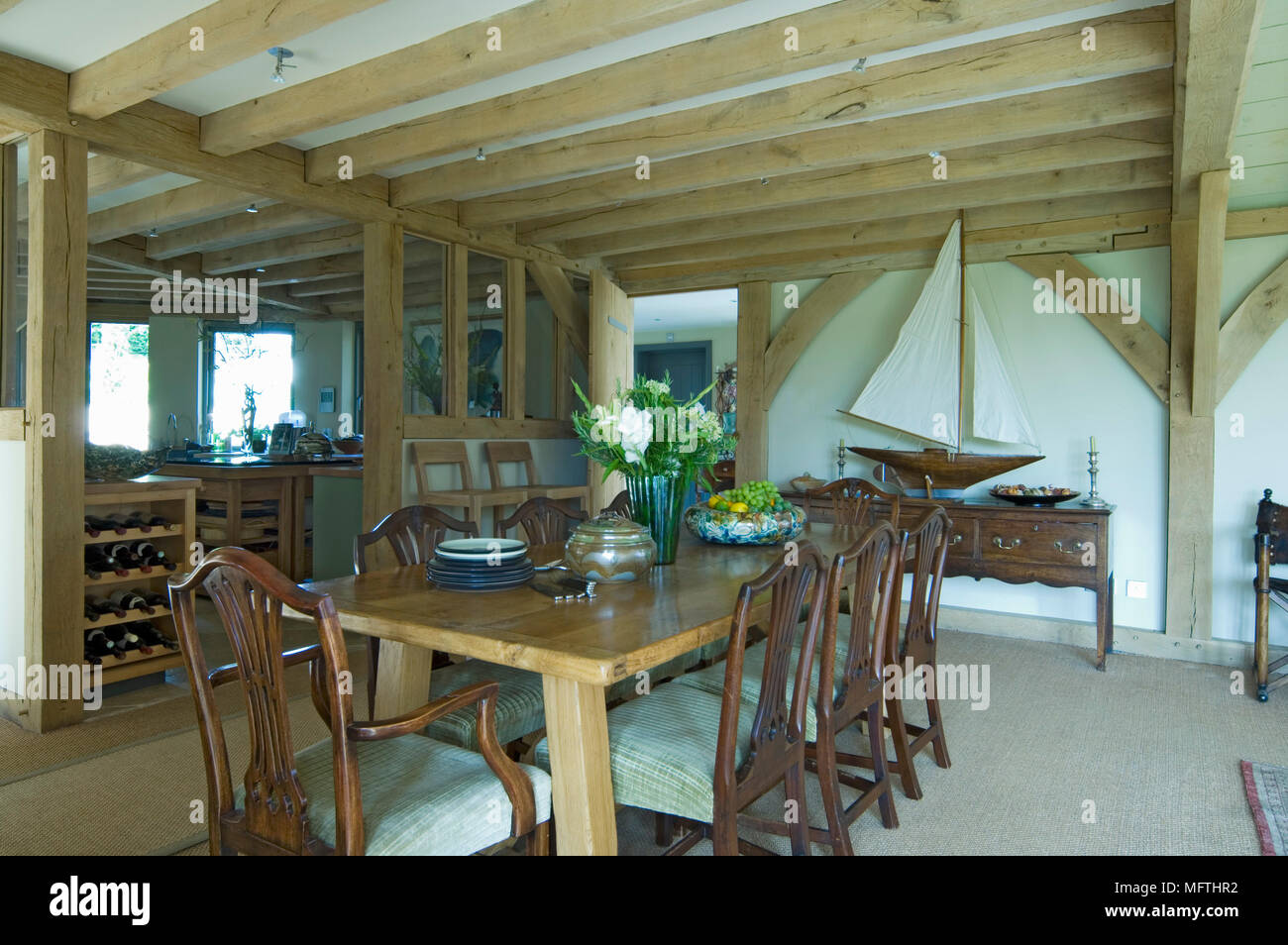 Dining room with wooden table and chairs under exposed wooden beams and model boat in background Stock Photo