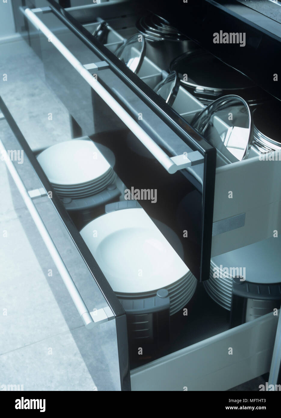 A detail of saucepans and plates in modern kitchen drawers Stock Photo