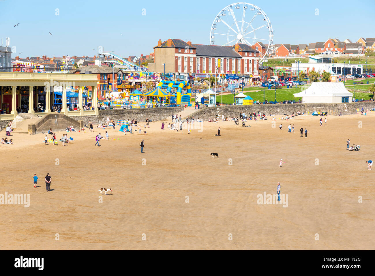 People enjoying a walk on the beach and sitting in the sun on a warm spring day at Barry Island, Wales Stock Photo