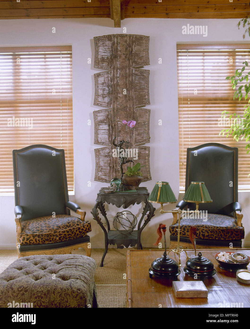 Sitting Room With Upholstered Leather And Animal Print Armchairs Bamboo Cane Coffee Table Tufted Footstool And Wall Art Between Windows Stock Photo Alamy